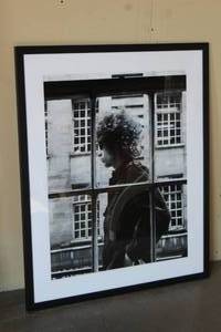 lot 48 image: BOB DYLAN 1966. FRAMED PHOTO OF BOB DYLAN WALKING PAST A SHOP WINDOW IN LONDON 1966 NUMBERED 00245 PHOTO BY MIRRORPIX 42X35