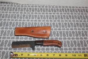 lot 113 image: HAND FORGED CARBON STEEL HUNTING BULL CUTTER BLADE WITH HAND CARVED HANDLE AND LEATHER SHEATH