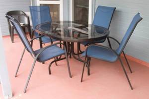 lot 53 image: SUNBEAM 5-PIECE OUTDOOR PATIO DINING SET WITH ROUND GLASS TOP TABLE  AND 4- NAVY FLEX COMFORT STACKING CHAIRS
