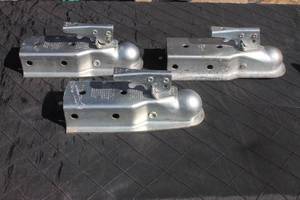 lot 11 image: Set of three galvanized steel trailer couplers with lever-locking mechanisms, showing light surface wear.