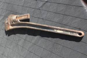 lot 15 image: Vintage heavy-duty cast iron pipe wrench with an adjustable knurled nut, showing age-related patina and surface rust.