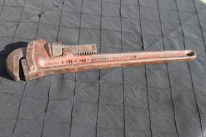 lot 16 image: Vintage heavy-duty cast iron pipe wrench with an adjustable knurled nut, showing age-related patina and surface rust.