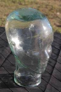 lot 20 image: Vintage life-size clear glass mannequin head with subtle greenish tint and molded facial features.