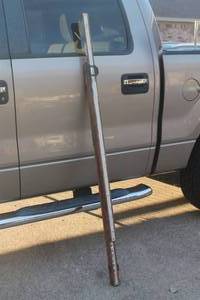lot 25 image: Vintage wooden surveyors leveling rod leaning against a pickup truck, featuring printed measurements and brass hardware