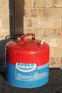 lot 26 image: Vintage Eagle Manufacturing Co. 5-gallon red and blue metal gasoline safety can, model KES-5, featuring a top carrying handle and flexible pour spout.