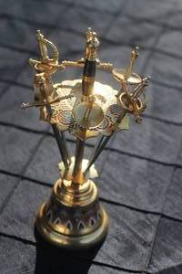 lot 39 image: Vintage Toledo-style brass cocktail pick set featuring miniature ornate swords in a matching stand with colorful enameled details.