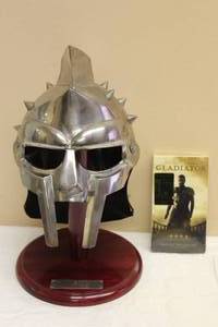 lot 38 image: GLADIATOR THE HELMET OF MAXIMUS FACTORY X2000 AD WITH WOOD STAND & GLADIATOR MOVIE VHS TAPE